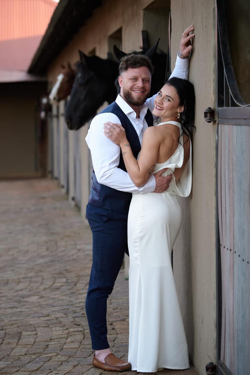 Wedding couple standing at barns after ceremony with horses in background at Lezar Opstal Heidelberg Gauteng