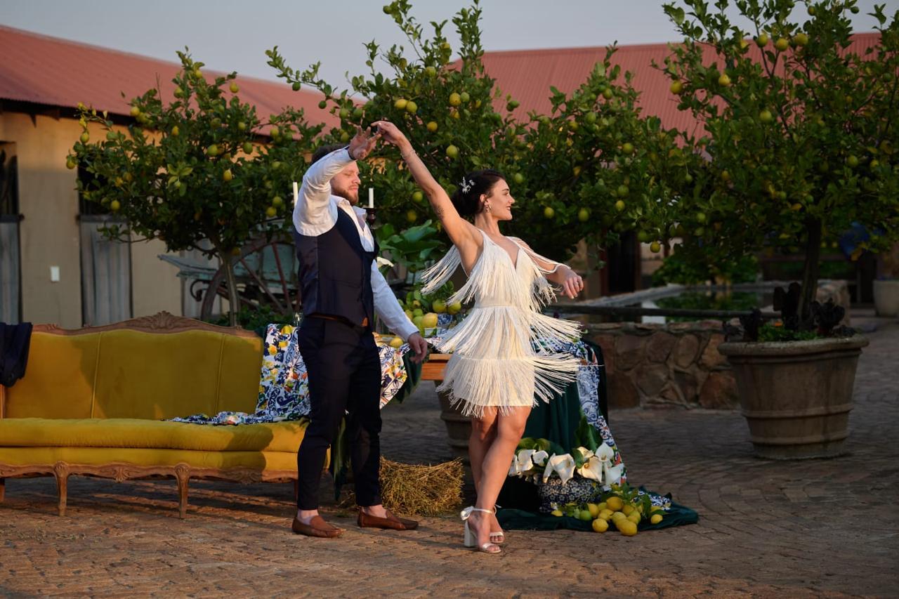 Newlywed couple taking photos at barns with yellow couch and flowers, husband twirling bride at Lezar Opstal Heidelberg Gauteng