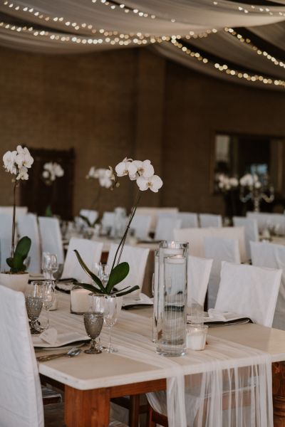 Wedding reception décor featuring elegant white flower centrepieces on decorated tables at Lezar Opstal Heidelberg